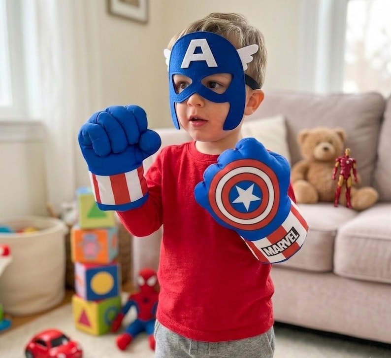 May include: A child wearing a Captain America mask and boxing gloves. The blue mask has a white "A" and wings. The gloves are blue with red and white stripes and a Captain America shield design. The word "MARVEL" is printed on the gloves.
