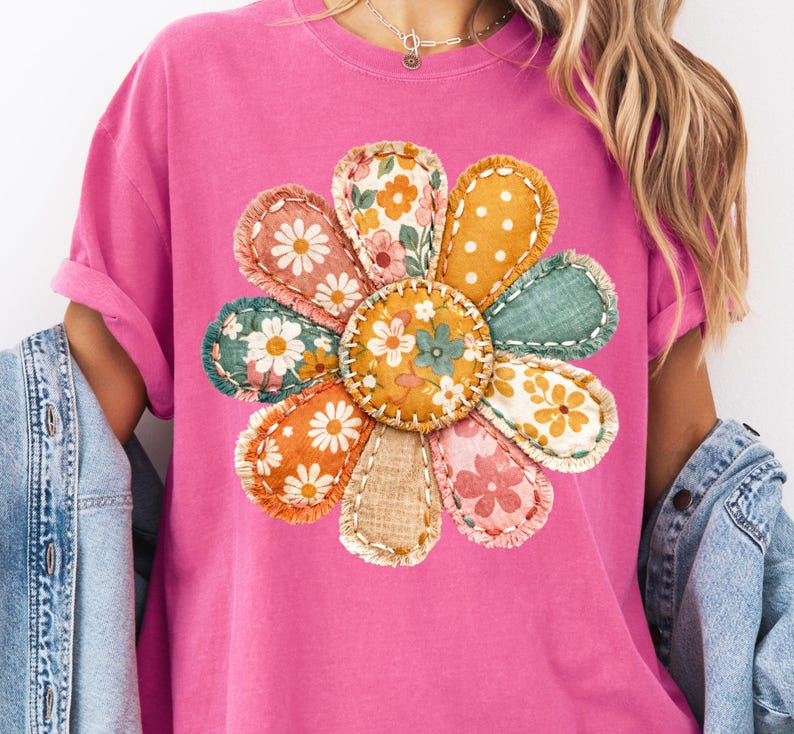 Może przedstawiać: Jasnor&oacute;żowa koszulka z dużym, kolorowym wzorem kwiatowym. Kwiat wykonany jest z r&oacute;żnych naszywek z tkaniny z kwiatowymi i groszkowymi wzorami, zszytych razem. Koszulka ma podwinięte rękawy.