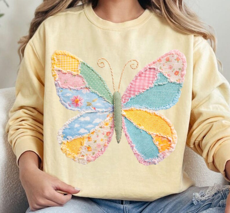 May include: A light yellow sweatshirt featuring a large, patchwork butterfly design. The butterfly wings are composed of various fabric patterns in pastel colors, including floral, gingham, and solid hues. The butterfly's body is green, and the antennae are made of twine.