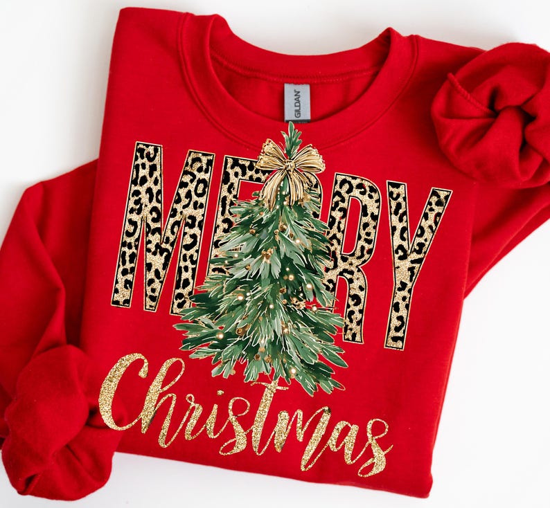 K&ouml;nnte beinhalten: Ein rotes Sweatshirt mit dem Schriftzug "MERRY Christmas" in goldfarbenem Glitzer. Das Wort "MERRY" hat ein Leopardenmuster. Ein gr&uuml;ner Weihnachtsbaum mit goldenen Ornamenten und einer goldenen Schleife befindet sich in der Mitte.