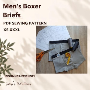 Op de afbeelding: Een PDF-naaipatroon voor boxershorts in maten XS-XXXL, met papieren patronen, een schaar met oranje handvatten, twee klossen garen en een geel meetlint op een lichtgrijze boxershort met een zwarte tailleband.