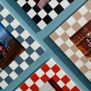 May include: An overhead shot of four photo frames with checkerboard patterns in black, tan, red, and blue. The frames are arranged on a light blue background, with photos visible inside the frames. The frames are a decorative element.