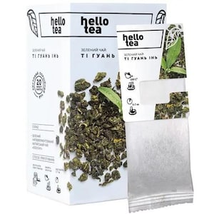 Op de afbeelding: Een witte rechthoekige doos Hello Tea groene thee met een afbeelding van losse theeblaadjes en een enkel theezakje ervoor. De verpakking bevat de tekst Hello Tea, Ti Guan Yin en iconen die de zetinstructies en 20 theezakjes aangeven.