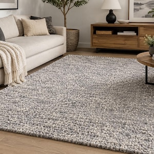 May include: A rectangular area rug featuring a thick, chunky knit texture with a variegated color palette of charcoal gray, light gray, and off-white yarns. The rug has a dense, looped pile construction that creates a consistent, nubby surface appearance.