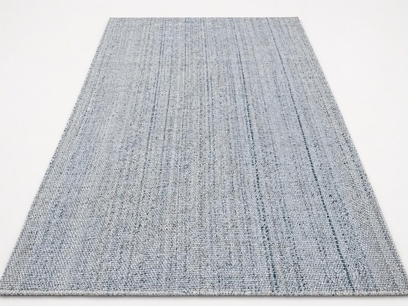 May include: A rectangular, light blue rug with a textured weave. The rug has a subtle pattern of vertical lines, creating a simple yet elegant design. The rug is suitable for various interior spaces.