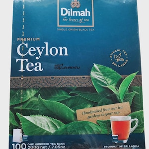 Könnte beinhalten: Eine rechteckige Schachtel Dilmah Premium Ceylon Tee mit dunkelblauem Hintergrund und grünen Teeblättern. Der Text lautet Dilmah, Premium Ceylon Tea und Handpicked from our tea gardens to your cup. Enthält 100 Teebeutel, 200g net / 7.05oz.