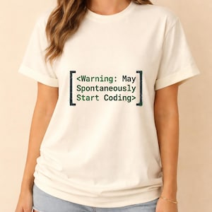 Puede incluir: Una camiseta de manga corta color crema con texto en verde oscuro entre corchetes que dice: <Warning: May Spontaneously Start Coding>. La prenda tiene cuello redondo y un corte estándar, con el gráfico centrado en la zona del pecho.