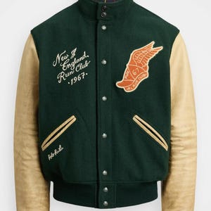 Puede incluir: Chaqueta universitaria verde y beige con cuello alzado y botones de presión. Cuenta con mangas de cuero beige, un parche "New England Run Club" y un emblema de zapato alado. Incluye el texto "Polo R.L."