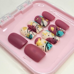 Mat bordeauxrode pers op de nagels: abstracte handgemaakte goudfolie-nagelset
