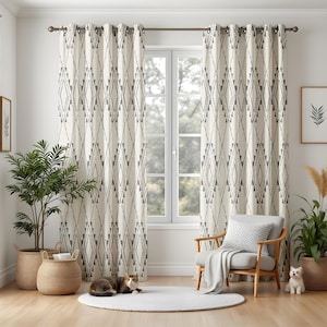 Puede incluir: Cortinas color crema con un patrón geométrico de diamantes en gris cuelgan de una barra sobre una ventana. Un gato descansa sobre una alfombra blanca frente a la ventana. Una silla de madera con un cojín y una manta grises está a la derecha.