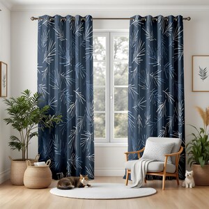 May include: Dark blue curtains featuring a white and pale blue leaf design. The curtains are hung in front of a window. A chair, plants, and a cat are in the room. The curtains have metal eyelets.
