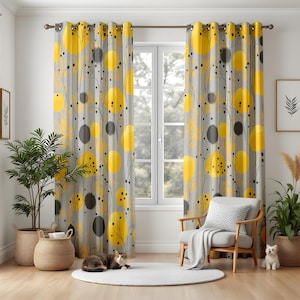 Puede incluir: Cortinas grises con un patrón repetido de círculos amarillos y puntos negros. Las cortinas cuelgan frente a una ventana. La habitación está decorada con plantas y una silla.
