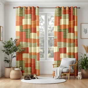 May include: A pair of patterned window curtains. The curtains feature a patchwork design with rectangular blocks in shades of orange, green, and cream, accented with white linear details. The curtains are hung on a dark metal rod in front of a window.
