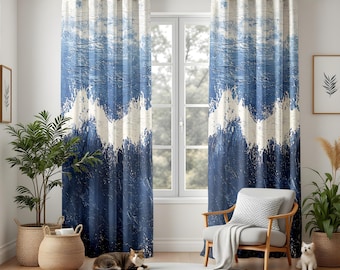 Può includere: Un paio di tende con motivo astratto blu e bianco con un design strutturato e pittorico. Le tende presentano un motivo a forma di onda e sono appese davanti a una finestra. La stanza ha una palette di colori neutri con una sedia, piante e un gatto.