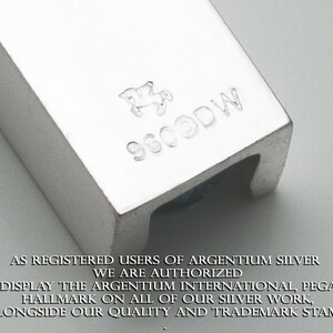 May include: Close-up of a silver hallmark stamp with the text "9600DW" and a stylized horse design. The text "AS REGISTERED USERS OF ARGENTIUM SILVER WE ARE AUTHORIZED TO DISPLAY THE ARGENTIUM INTERNATIONAL, PEGASUS HALLMARK ON ALL OF OUR SILVER WORK, ALONGSIDE OUR QUALITY AND TRADEMARK STAMP." is visible below the stamp.
