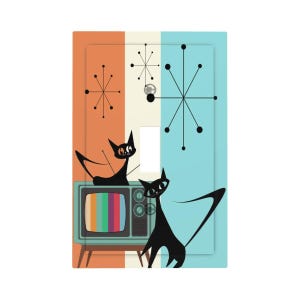May include: A decorative light switch cover with a retro design. The cover features a teal and orange striped background with black cat silhouettes and a vintage television. Atomic starbursts and a mid-century modern aesthetic.