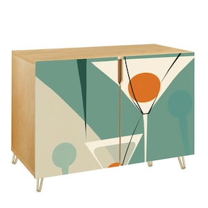 May include: A wooden cabinet with a light wood finish and gold-colored legs. The cabinet doors feature a retro-style design with martini glasses in teal, cream, and orange. The cabinet is a stylish storage solution.