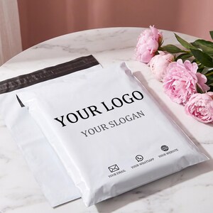 Może przedstawiać: Biała plastikowa koperta wysyłkowa z czarnym paskiem samoprzylepnym u góry. Z przodu znajduje się nadrukowany tekst YOUR LOGO i YOUR SLOGAN oraz małe ikony z informacjami kontaktowymi e-mail, WhatsApp i strony internetowej.