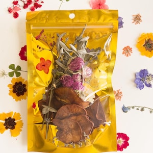 Könnte beinhalten: Ein wiederverschließbarer Beutel aus Gold, gefüllt mit getrockneten Blumen und Blättern. Der Beutel ist umgeben von losen getrockneten Blumen in verschiedenen Farben, darunter Rosa, Lila, Gelb und Weiß.