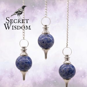 May include: Three blue and silver pendulums hanging from silver chains. Each pendulum has a spherical, speckled blue stone and a silver metal cap and point. The image includes the text "Secret Wisdom" with a raven illustration.