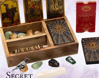 May include: A wooden box set with tarot cards, crystals, and a smudge stick. The tarot cards feature illustrations and the box has compartments for storage. The set includes a deck of cards with an eye design, and the words "Secret Wisdom" are printed on the bottom.