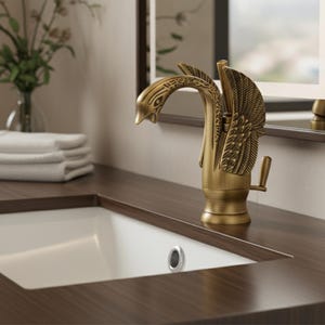 Può includere: Un rubinetto color bronzo con un design a forma di cigno, con un beccuccio curvo e dettagli alari. Il rubinetto è montato su un piano di lavoro marrone scuro sopra un lavabo bianco, creando un'estetica da bagno lussuosa.