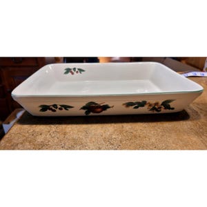 Puede incluir: Fuente rectangular de cerámica blanca con ribete verde e ilustraciones de frutas. El plato presenta imágenes de cerezas, manzanas y flores. Un artículo de cocina clásico.