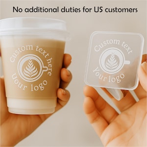 Op de afbeelding: Een beige koffiebeker met een wit deksel en een vierkante doorzichtige onderzetter, beide met een koffiekopje-ontwerp met de tekst "Custom text here" en "Your logo". De afbeelding bevat ook de tekst "No additional duties for US customers".