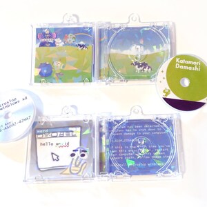 May include: A collection of CDs and CD cases with colorful graphics. One CD case features a cow in a field, another displays a computer error message. Other CDs have text that reads "microstop winblows xd" and "Katamori Damashi".