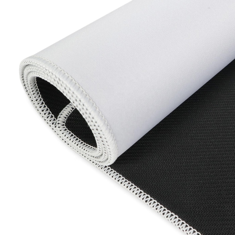 May include: Rolled-up white mousepad with a black, textured underside. The edge is finished with white stitching. The mousepad is designed for computer use.