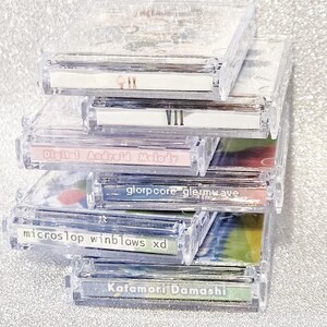 May include: A stack of clear plastic CD cases with colorful inserts. The labels on the cases read "VII", "Digital Android Melody", "glorpoore glerwave", "microslop winblows xd", and "Katamori Damashi".