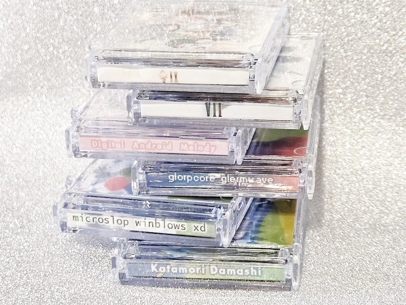 May include: A stack of clear plastic CD cases with colorful inserts. The labels on the cases read "VII", "Digital Android Melody", "glorpoore glerwave", "microslop winblows xd", and "Katamori Damashi".
