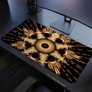 May include: A black desk mat with a gold geometric design and the text "14 x 24in Deskmat". The design features a central circular pattern with radiating lines and circular accents. The desk mat measures 14 inches by 24 inches.