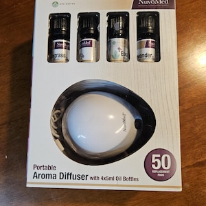 May include: A white portable aroma diffuser with a cord and 50 replacement pads. The diffuser is packaged with four 5 ml bottles of essential oils: lemongrass, lavender, eucalyptus, and tea tree.
