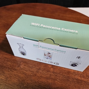 May include: A rectangular box for a WiFi panorama camera, with a light green top and white sides. The text "WiFi Panorama Camera" and "Easy to achieve real-time remote viewing" are printed on the box. Images of the camera are also shown.