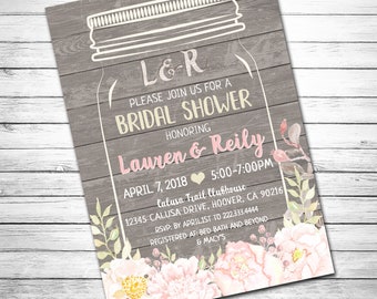 May include: A bridal shower invitation with a mason jar design. The invitation features the names "Lauren & Reily" in pink, with event details and floral accents on a gray wood-grain background.
