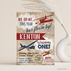 May include: A red, white, and blue airplane themed first birthday invitation for a boy named Kenton. The invitation features a vintage airplane design with the text "My, oh my... this year has flown by! Kenton is turning one!" and includes details for the party, including the date, time, and location. RSVP information is also included.