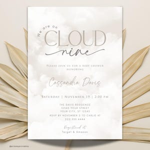 May include: A baby shower invitation with a cloud theme. The invitation is white with a grey watercolour background and the text "We are on Cloud nine" in grey. The invitation also includes the name "Cassandra Davis" and the date and time of the shower.
