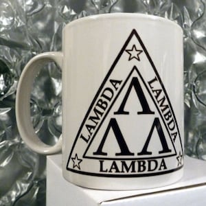 May include: White ceramic coffee mug with a black triangle design featuring the word "Lambda" repeated three times and a star at each point of the triangle.
