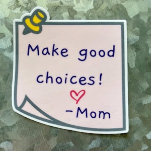 May include: A sticker with a light pink background and a gray border. The sticker has the text "Make good choices!" in dark blue, a red heart, and the word "-Mom" in dark blue. A yellow and black pushpin graphic is at the top.