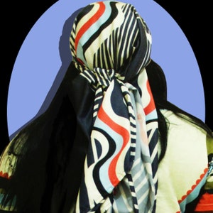 May include: A patterned headscarf with a blue, red, and white wave design. The scarf is tied at the back of the head, with long black hair visible. The background is a light blue circle against a black backdrop.
