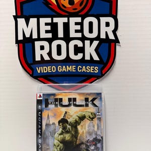May include: A PlayStation 3 video game case for The Incredible Hulk featuring the green character in a city setting, with a logo sign above reading Meteor Rock Video Game Cases with a graphic of a flaming meteor.