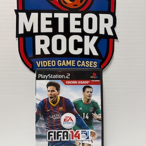 Op de afbeelding: Een PlayStation 2 videogamehoesje voor FIFA 14 Edición Legado met twee voetballers op de cover. Het hoesje staat voor een bord met de tekst Meteor Rock Video Game Cases en een afbeelding van een brandende meteoor.