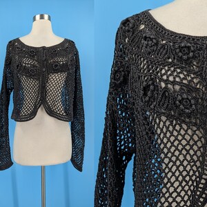 May include: A black crocheted cardigan with a button closure and a delicate floral pattern. The cardigan is lightweight and has a loose fit.