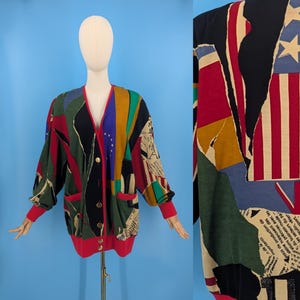 以下が含まれることがあります： 赤、白、青のアメリカ国旗、緑と黄色の旗、白黒の新聞プリントなど、さまざまな生地とパターンを組み合わせたパッチワークデザインのカラフルなカーディガン。カーディガンはボタン留めフロントと長袖です。