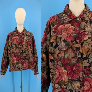 May include: A long-sleeved button-up shirt with a floral print in shades of red, brown, and green on a black background.