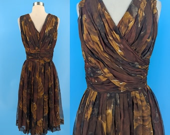 May include: A vintage sleeveless dress in shades of brown, gold, and black. The dress features a V-neckline, a fitted waist, and a flowing skirt. The fabric has a watercolor-like pattern. The dress is displayed on a mannequin against a blue background.