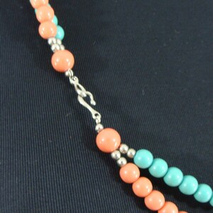 May include: A two-strand necklace with alternating coral and turquoise beads. The necklace has a silver clasp.