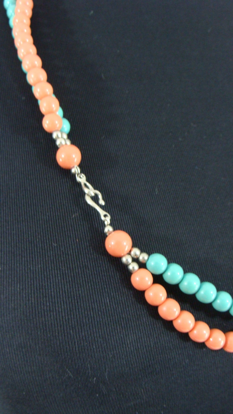 May include: A two-strand necklace with alternating coral and turquoise beads. The necklace has a silver clasp.
