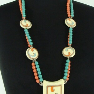 May include: A double strand necklace with coral and turquoise beads and a large pendant with a swirl design.